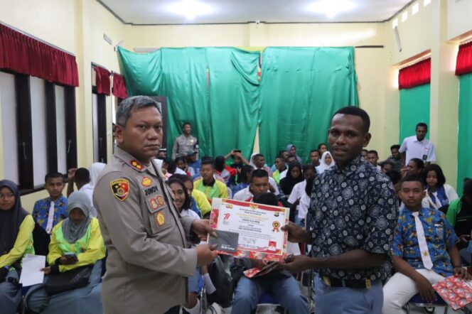 
 Kapolres Teluk Bintuni, Junov Siregar saat memberikan piagam dan buku tabungan kepada seorang siswa.