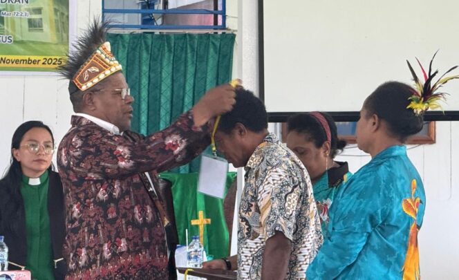 
 Sekretaris Klasis GKI Teluk Bintuni, Pdt. Johanis Lanta mengalungkan tanda peserta secara simbolis kepada salah satu utusan jemaat.