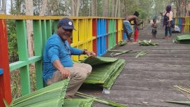Petrus Kasihiw tengah menganyam daun sagu untuk dijadikan atap pondok di kampung Masina, Bintuni.