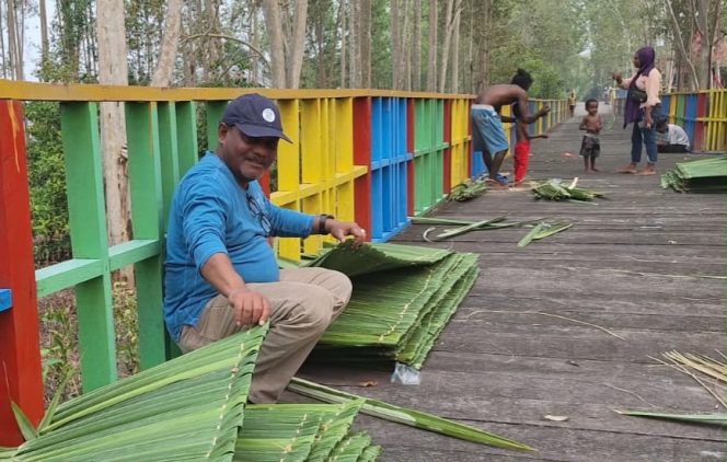 
 Petrus Kasihiw tengah menganyam daun sagu untuk dijadikan atap pondok di kampung Masina, Bintuni.